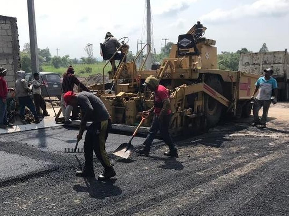 Cuadrilla y maquinaria pavimentando un camino rural