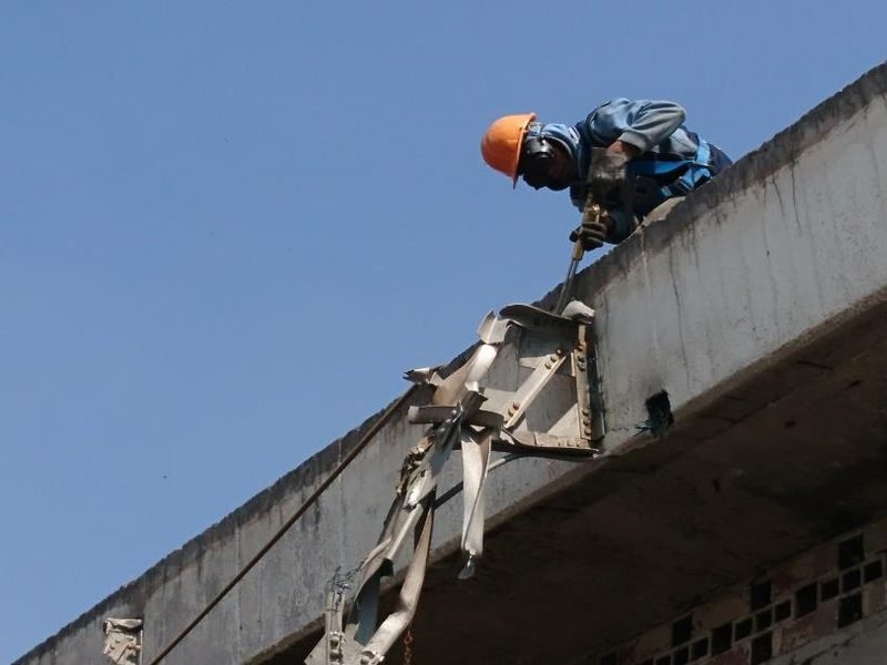 Operador demoliendo una losa en altura con martillo hidráulico