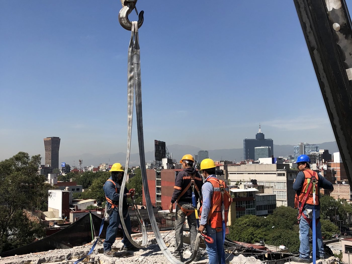 Cuadrilla trabajando sobre la losa demolida de un edificio, con grúa y la ciudad al fondo
